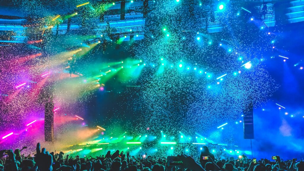 Escenario de concierto con luces de colores y confeti sobre el público