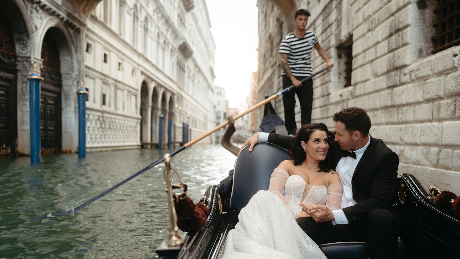 Pareja de recién casados viajando en góndola por un canal de Italia