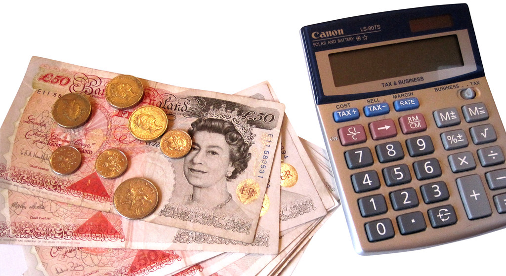 Calculadora junto a billetes y monedas para calcular el rendimiento real de una inversión