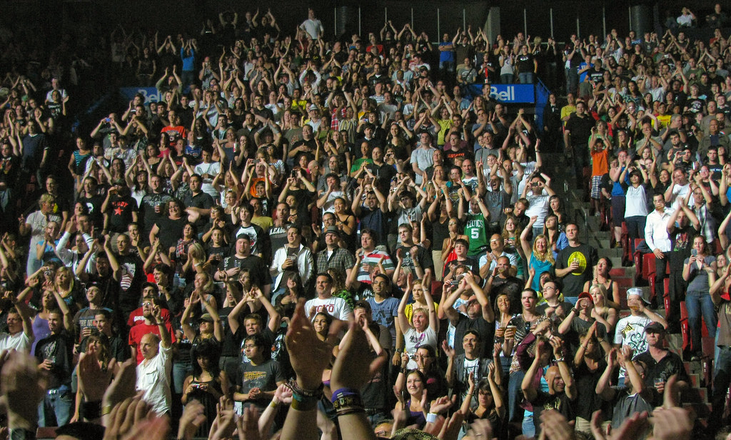 Público con las manos en alto frente al escenario de un concierto
