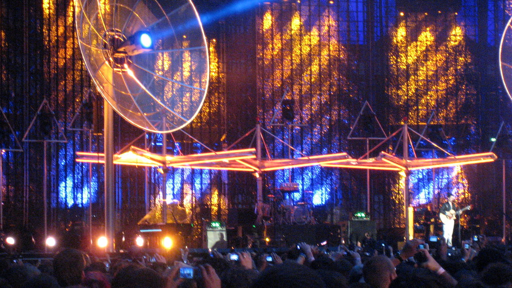 Escenario de concierto iluminado ante una multitud durante una gira musical