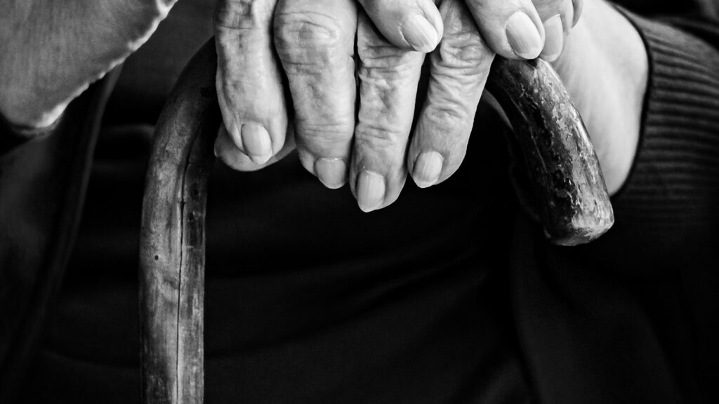 Manos de una persona adulta mayor apoyadas en un bastón