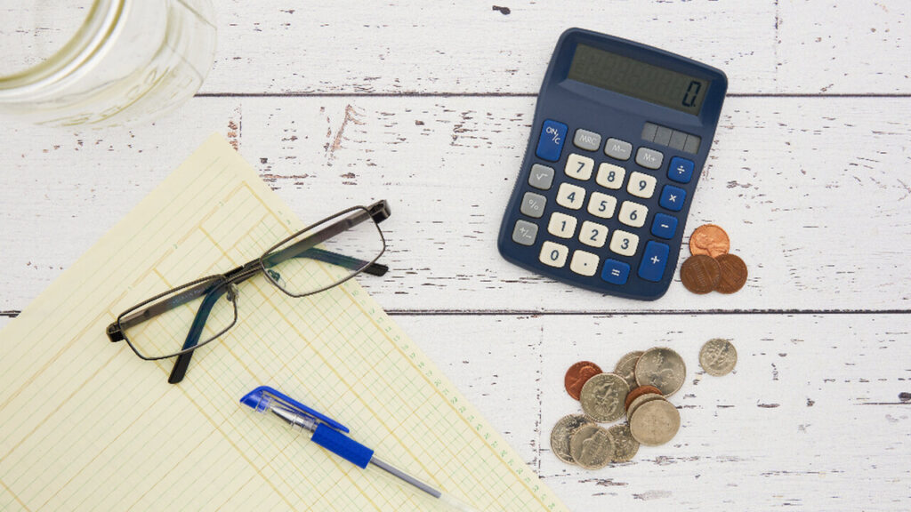 Calculadora, lentes y monedas sobre una mesa
