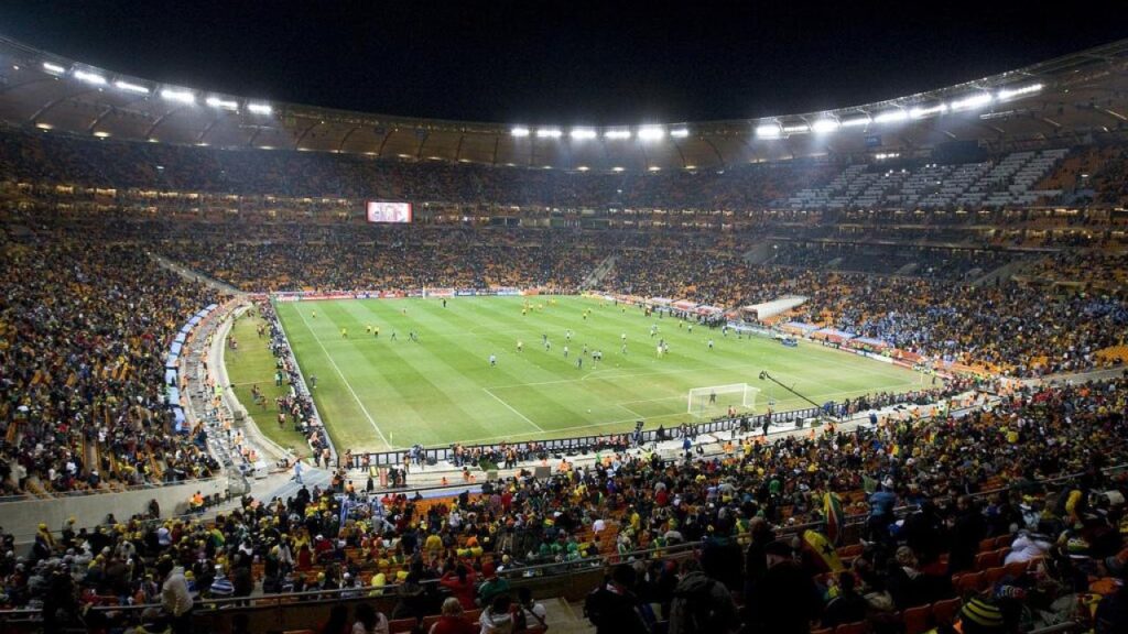Estadio de fútbol lleno de aficionados durante un partido nocturno
