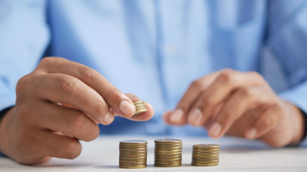 Manos apilando monedas que simbolizan el crecimiento del ahorro en Cetes