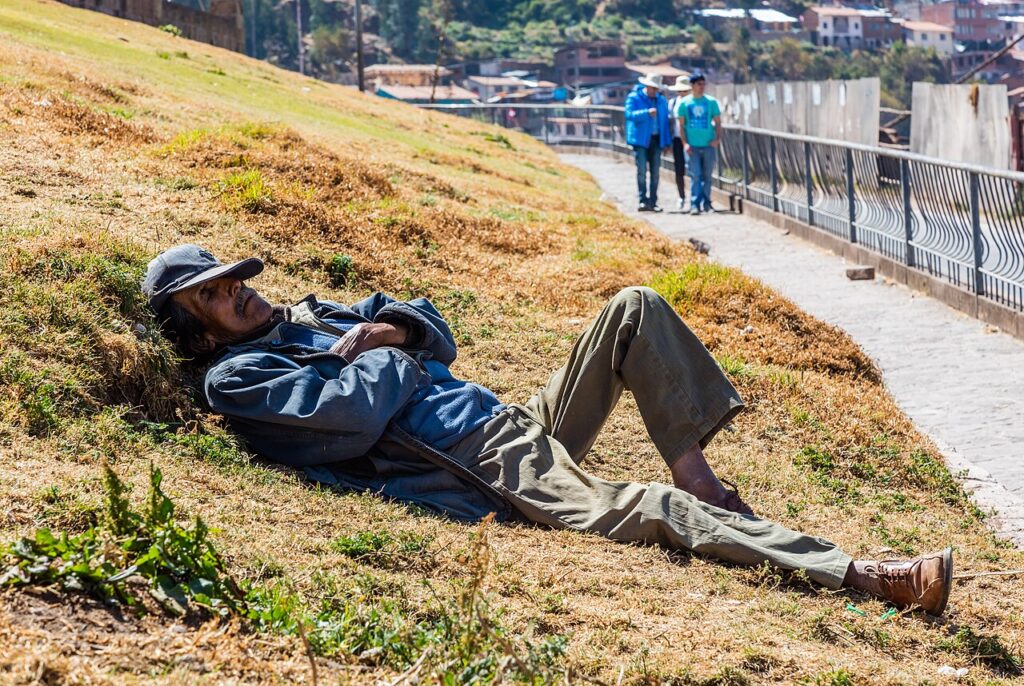 Hombre recostado echando una siesta al aire libre en San Cristóbal, Cusco