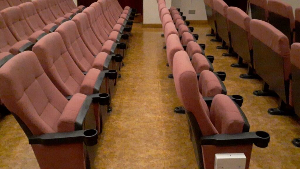 Sala de cine con pantalla iluminada durante una función